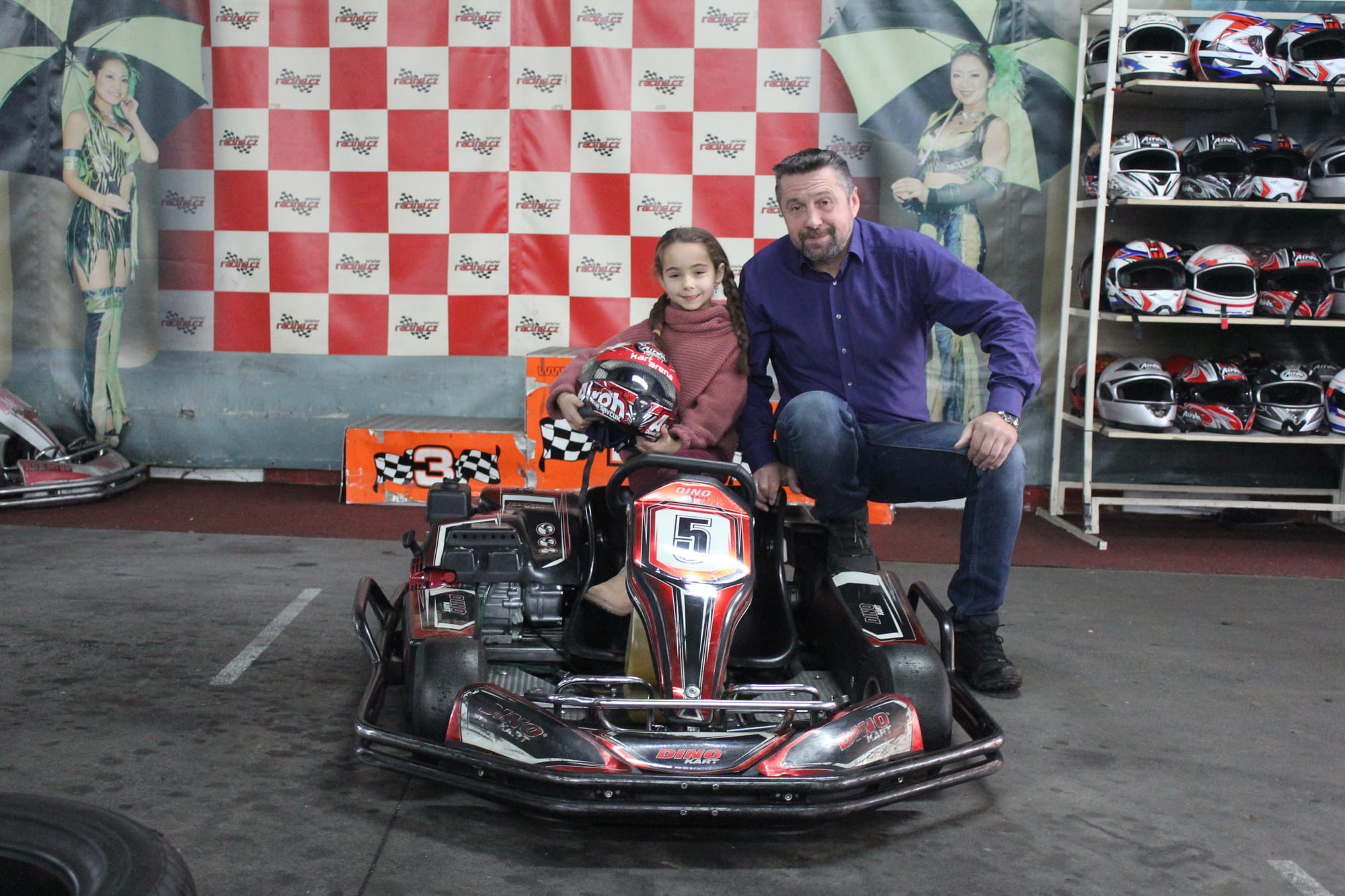 Jezdci u motokár a regál s helmami v A-Kart Arena